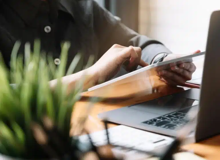 a person's arms scrolling on a tablet they're holding sitting at a desk