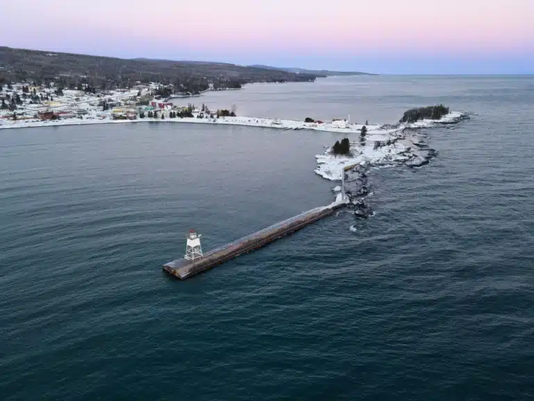 the grand marais lighthouse with a purple and blue sky and snowy town behind