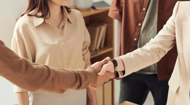 two people shaking hands while two others stand next to them